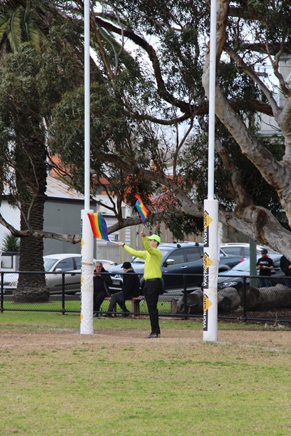 The goal umpire waves his rainbow flags.